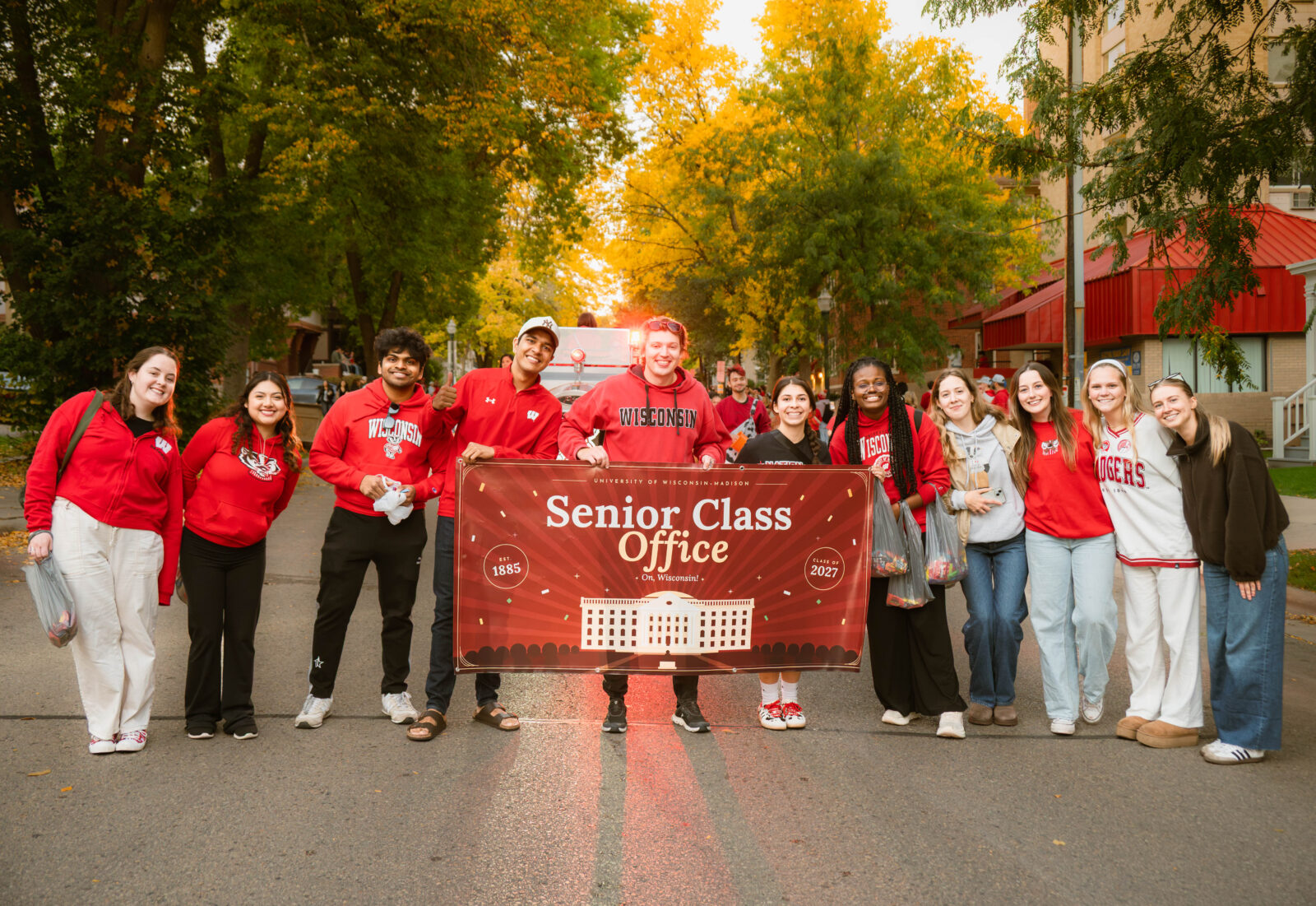 Seniors pose with a Senior Class Office poster on the street